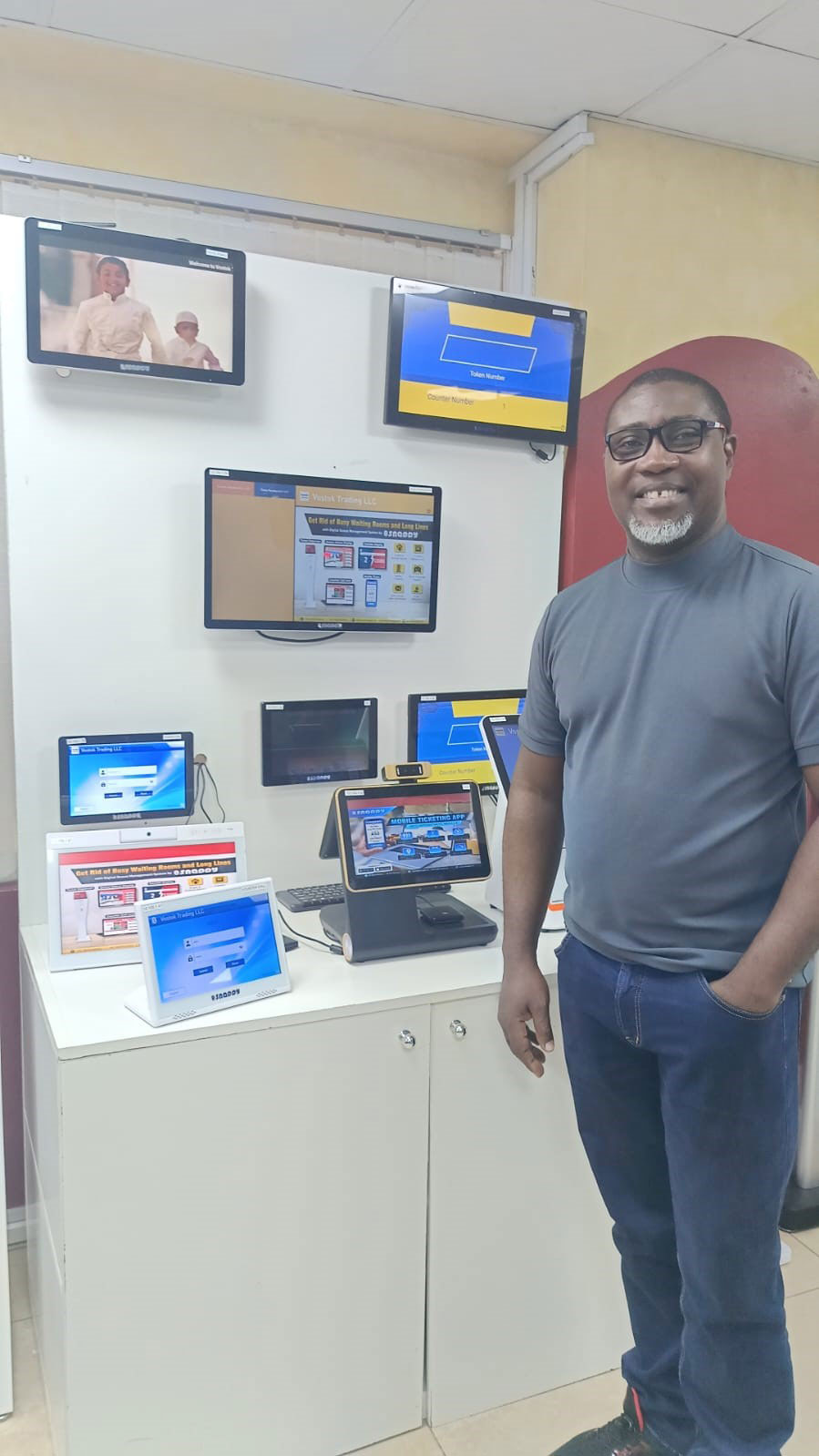 Ghana dealer visiting Vostok Headquarters, exploring queue management system and digital solutions displayed on various screens and devices.